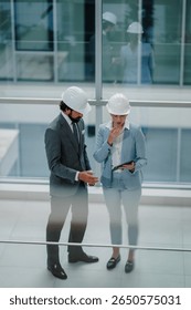 Two architects are discussing a project using a tablet in a modern office building, showcasing teamwork and technology in the architecture industry