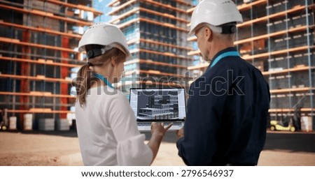Two Architects And Engineers Discuss 3D BIM Model At Busy Construction Site.