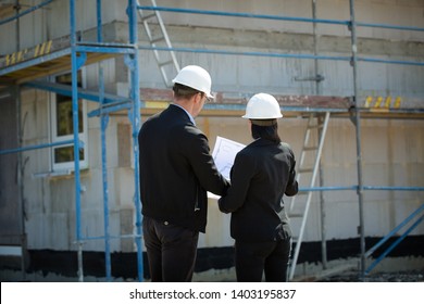 Two architects a man and a woman in construction in white helmets	 - Shutterstock ID 1403195837
