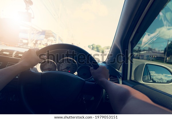 Two arm turns the steering wheel\
of a car. Blurred of the road with under the retro\
colors.
