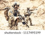 Two armed US army commandos or military scouts equipped with radio headset moving forward in sands during enemy area reconnaissance. Special forces operation, long range surveillance mission in desert