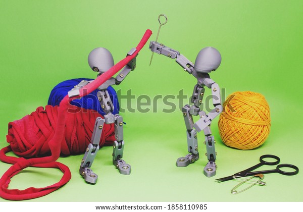 Two\
articulated dolls, in cooperation, simulate the creation and\
development of some art project. In this still photography, toys\
and sewing materials were used to create the\
scene.