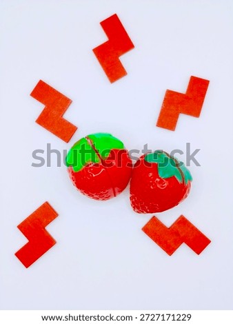 Two artificial strawberry forms isolated on white background representing food replication material precision and synthetic food design experimentation.