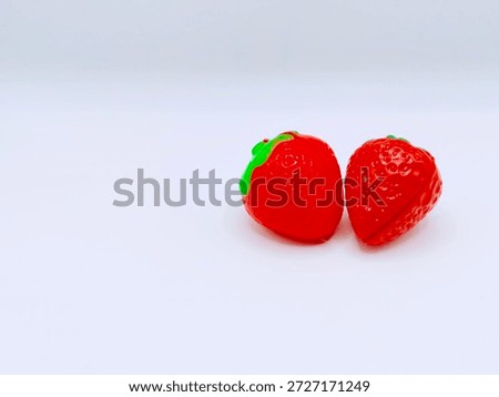 Two artificial strawberry forms isolated on white background representing food replication material precision and synthetic food design experimentation.