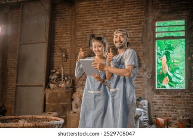 Two artisans proudly display their vibrant pottery in a rustic studio, showcasing their skills - Powered by Shutterstock