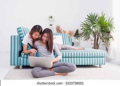 Two Asia Woman Using Laptop Computer To Shopping Online And Sitting On Sofa In Living Room At Home.Leisure Digital Lifestyle.Lesbian Lgbt Couple