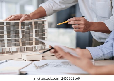 Two asian architect engineer inspecting building model and blueprint of drawing architecture plan while discussion to designing new project about building model and construction plan in office. - Powered by Shutterstock