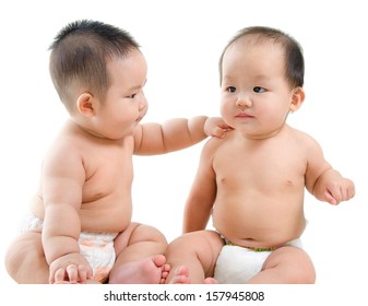 Two Asian Babies Having Baby Talk, Sitting Isolated Over White Background.