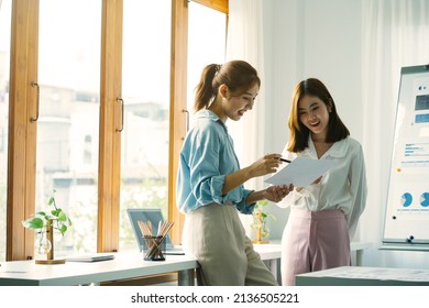 Two Asian business colleagues standing and looking at some documents in the office.. - Shutterstock ID 2136505221