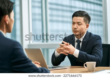 two asian business men sitting at desk face to face in modern office having a discussion Foto stock © 
