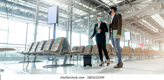 two asian business partners with face mask protection social distancing new normal lifestyle Business travellers walking in airport with luggage - Powered by Shutterstock