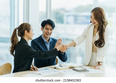 Two Asian Business Partners Successful Handshake Together In Front Of Group Teamwork Casual Business Clapping Hands Winning Success Agreement In Modern Office.Partnership Approval And Teamwork