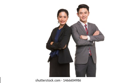 Two Asian Business People Standing And Posing, Woman Crossed Her Arms, Man Putting Hand In Pants's Bag, Isolated On White Background Copy Space On Left Side.