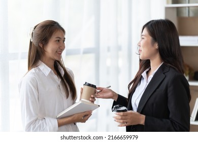 Two asian business woman, talking, advising each other in office, training team people speaking explaining strategy at marketing workshop concept. - Shutterstock ID 2166659979