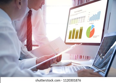 Two Asian Businessmen analysing on business loan comparison on desktop and notebook computer with colorful pie and bar graphs. - Powered by Shutterstock