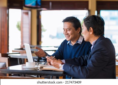 Two Asian Businessmen Having Meeting In The Cafe