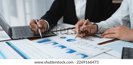 Two Asian businessmen met in the office and pointed to analysis charts and graphs of business growth and financial performance.