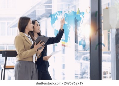 Two Asian Businesswoman working on digital analysis report Infographic dashboard and advisor showing plan in office, Digital marketing and finance.