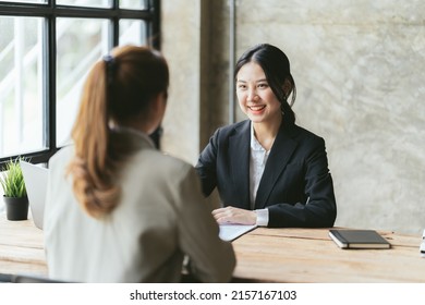 Two Asian Businesswomen Discussing Business Project Working Together In Office, Serious Female Advisor And Client Talking At Meeting, Focused Executive Colleagues Brainstorm Sharing Ideas.