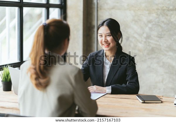 Two asian businesswomen discussing business\
project working together in office, serious female advisor and\
client talking at meeting, focused executive colleagues brainstorm\
sharing ideas.