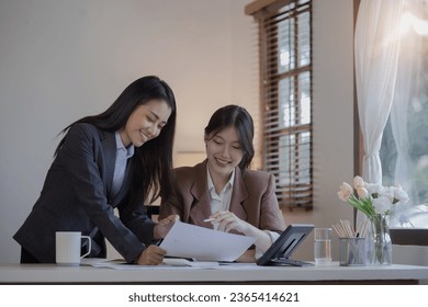 Two Asian businesswomen with friends and discussed their ideas at a meeting, Businesswoman talking with financial statement report together  at the office. - Shutterstock ID 2365414621