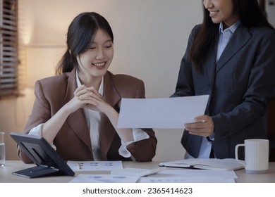 Two Asian businesswomen with friends and discussed their ideas at a meeting, Businesswoman talking with financial statement report together  at the office. - Shutterstock ID 2365414623