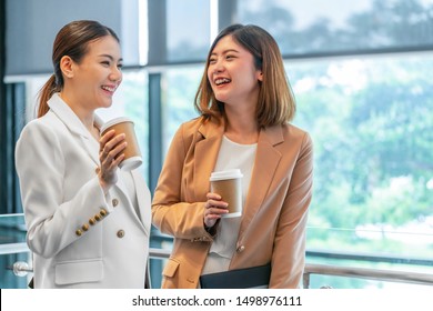 Two Asian Businesswomen Talking During Coffee Break In Modern Office Or Coworking Space, Coffee Break, Relaxing And Talking After Working Time, Business And People Partnership Concept