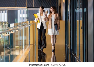 Two Asian Businesswomen Walking And Talking During Coffee Break In Modern Office Or Coworking Space, Coffee Break, Relaxing And Talking After Working Time, Business And People Partnership Concept