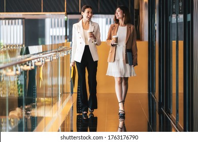 Two asian businesswomen walking and talking during coffee break in modern office or coworking space, coffee break, relaxing and talking after working time, business and people partnership concept