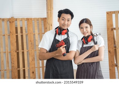 Two asian carpenter looking to camera at workplace. They holding stuff and looking to camera with smiling together. - Powered by Shutterstock