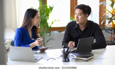 Two Asian Colleagues Worker Having A Small Talk, Discuss Their Work Project In The Office Together.