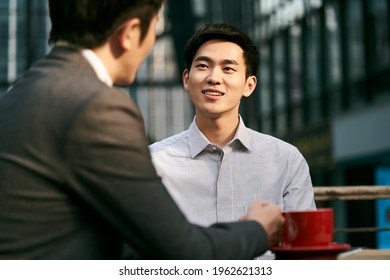 Two Asian Corporate Businesspeople Discussing Business At A Outdoor Coffee Shop