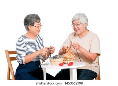 Two Asian elderly woman sit on chair and have activity of knitting, also talk together with smile in front of white background. - Powered by Shutterstock