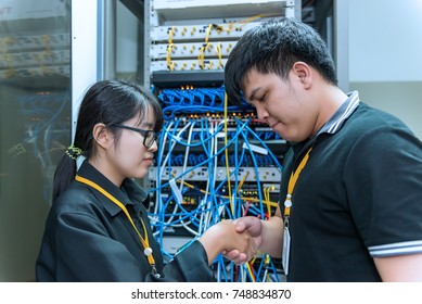 Two asian engineers working in the server room,Check the connection problems of computer networks,Thailand people,shaking hand after success work
