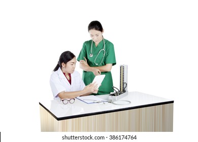 Two Asian Female Doctor Using Tablet Computer Reviewing Medical Chart, Isolated On White