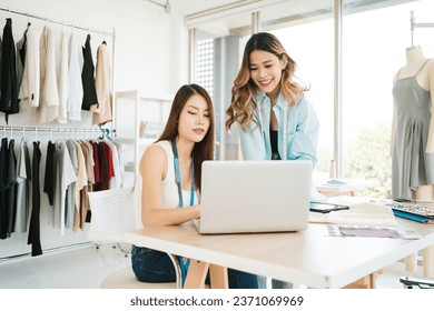 Two Asian female fashion designers or dressmakers brainstormed and discuss the design of the new collection with examples of fabrics and sketches on the laptop. Working together in the studio. - Powered by Shutterstock