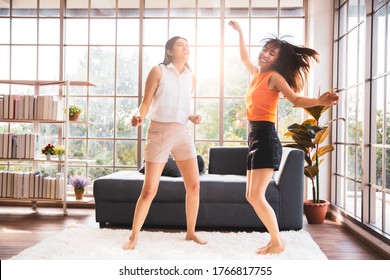 Two asian female friend dancing in living room at home, Happy stay home concept - Powered by Shutterstock