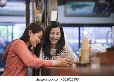 two asian female friends chatting in a traditional Japanese restaurant in Kyoto