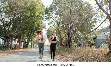 Two Asian Girl Friends In Sportswear Jogging Outdoor Together In The Morning. Happy Woman Running And Talking. Exercise Buddy And Healthy Lifestyle Concept