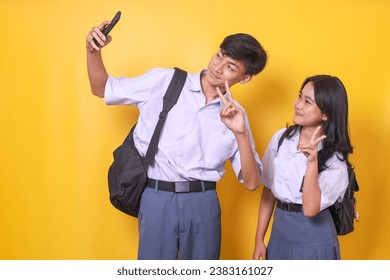 Two Asian high school students with bag wearing school uniform taking selfie photo together