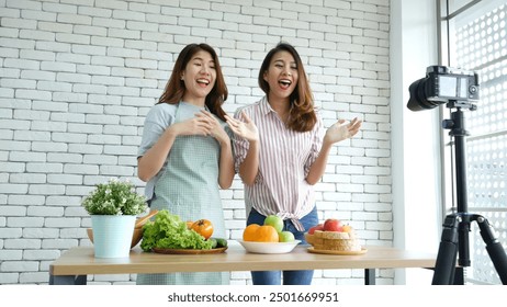 Two Asian influencer vlogger live review healthy lifestyle together. Two Young Women Friends blogger vlog Happy Lifestyle greeting Live Streaming. Vlog two women talk social media say hello broadcast - Powered by Shutterstock