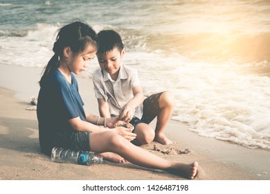 Two Asian Kids Is Helping Up Cleaning The Enviroment On The Beach