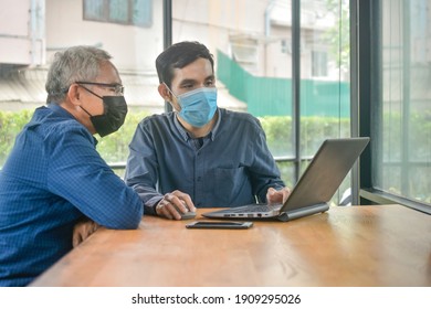 Two Asian man meeting business by laptop computer in cafe, Two people wear face mask prevent coronavirus covid19 - Powered by Shutterstock