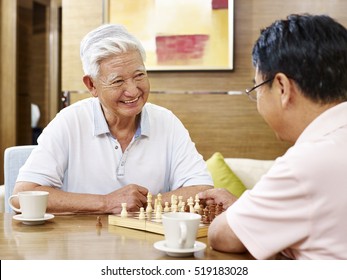 Two Asian Men Playing Chess Game At Home