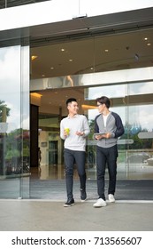 Two Asian Men Talk And Use Smart Phone Outside The Building