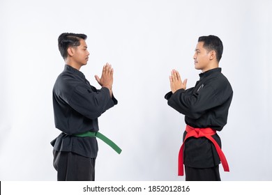 Two Asian Men Wearing Pencak Silat Uniforms Stand Opposite Each Other With Mutual Respect On The Isolated Background