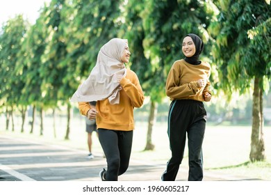 two asian muslim girls enjoy jogging together while chatting in the afternoon in the garden field