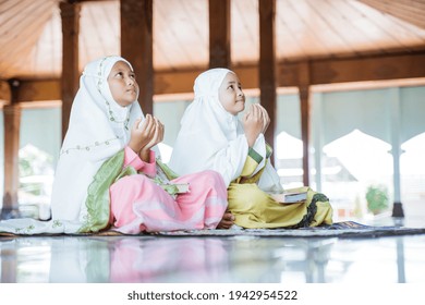 two Asian Muslim girls together sitting on the floor worship and prays for Allah
