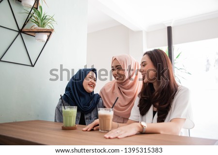 two asian muslim woman bestfriend together in cafe smiling to camera