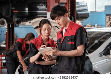  Two Asian professional mechanics, male supervisor engineer, and partner discuss and inspect repair work checklists at garage, service car maintenance, and fixing specialist occupations auto industry. - Powered by Shutterstock